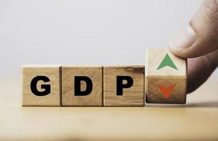Hand flipping wooden cube block which print screen up and down symbol with GDP increase and decrease , GDP is Gross Domestic Product concept. photo