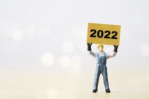 Worker man holding yellow paper with 2022 year for preparation happy new year and start new business plan. photo
