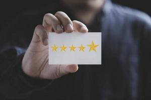 Businessman holding white paper with five yellow stars for client evaluation and customer satisfaction after use product and service concept. photo