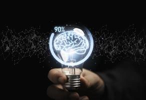 Businessman holding lightbulb with virtual brain and downloading icon progress for creative thinking solution and smart problem solving concept. photo