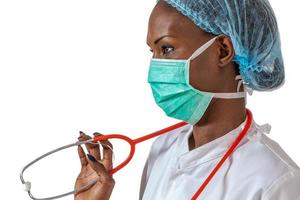 doctora africana americana, enfermera mujer con abrigo médico, gorra, con estetoscopio y máscara. foto
