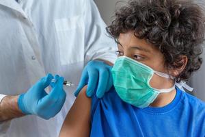 Male doctor in protective face mask latex gloves giving intramuscular vaccination protected patient's arm photo