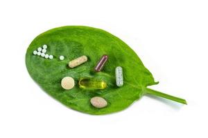 Homeopathy - A homeopathy concept with homeopathic medicine and food supplement on green leaves photo