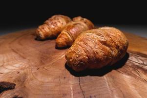 three Freshly baked croissant on a wooden Tray. Delicious and healthy breakfast photo