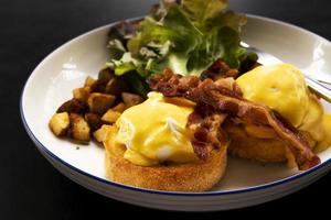 huevos benedicto tocino desayuno en la mesa foto