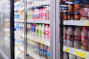 desenfoque de botellas de leche de productos lácteos en el estante del refrigerador en el supermercado foto