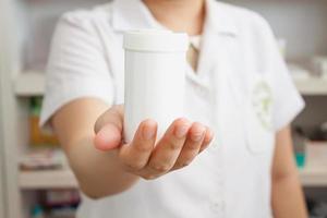 Pharmacist showing medicine bottle on her hand in the pharmacy photo