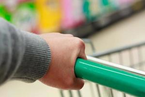Closeup hand and shopping cart at supermarket photo