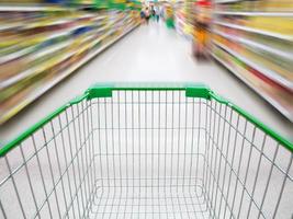 supermarket aisle with empty green shopping cart photo