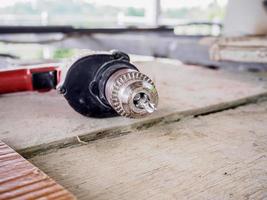 Close up electric drill at work site on wooden board photo