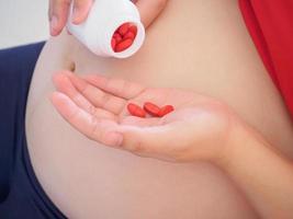 pregnant woman with vitamin pills on her hand photo