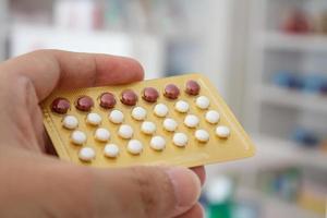 Close up of pharmacist hands holding contraceptive pills photo