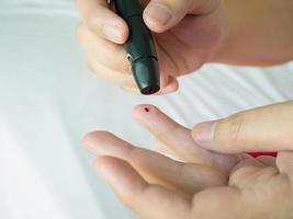 woman using lancelet on finger, diabetes test photo