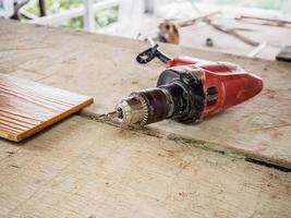 cierre un taladro eléctrico en el lugar de trabajo sobre una tabla de madera foto