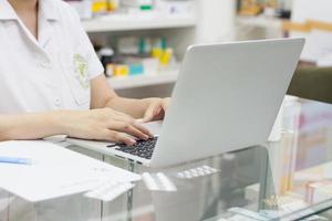 farmacéutico con computadora portátil y medicamentos en la farmacia foto