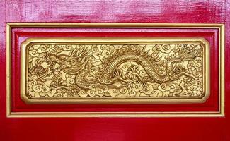 dragón chino dorado sobre fondo de madera roja foto