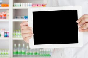 farmacéutico que muestra una tableta digital en blanco en la tienda de farmacia foto