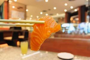 salmon sashimi in chopsticks with japanese restaurant interior photo