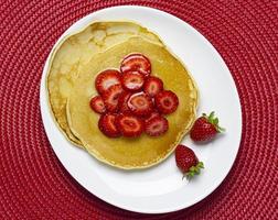 Topview of pancakes with strawberries and syrup photo
