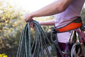 A rock climber prepares equipment for climbing, woman holds a rope, knot photo