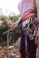 A rock climber prepares equipment for climbing, woman holds a rope, knot photo