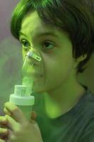 the child does inhalation, the boy inhales the medicine through the mask photo