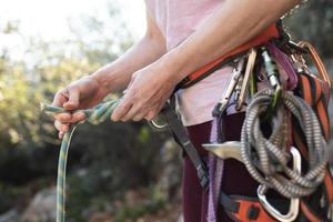 A rock climber prepares equipment for climbing, woman holds a rope, knot photo