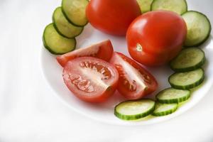 Slicing vegetables on a white plate tomatoes and cucumbers photo