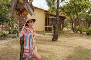 señora apoyada contra una palmera cerca de la playa en caraiva, bahia, brasil foto