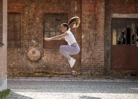 Mujer joven juping alto durante el entrenamiento en el entorno urbano. foto