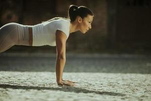 Young woman doing puhsups on the street photo