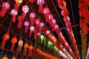 Linternas de papel bellamente formadas y coloridas se cuelgan frente a una pagoda para adorar al Señor Buda en un templo en el norte de Tailandia. foto