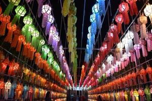 Beautifully shaped and colorful paper lanterns are hung in front of a pagoda to worship Lord Buddha in a temple in northern Thailand. photo