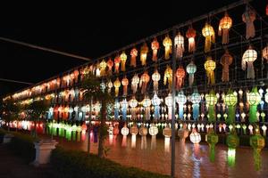 Beautifully shaped and colorful paper lanterns are hung in front of a pagoda to worship Lord Buddha in a temple in northern Thailand. photo