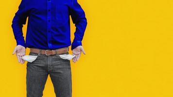 Man showing his empty pockets on yellow wall background. photo