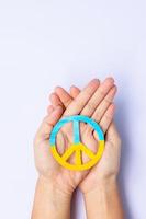 apoyo a ucrania en la guerra con rusia, manos sosteniendo el símbolo de paz con la bandera de ucrania. rezar, no a la guerra, detener la guerra, estar con ucrania y el desarme nuclear foto