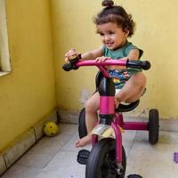 lindo niño pequeño shivaay conduciendo en bicicleta en el balcón de la casa durante el verano, dulce sesión de fotos de niño pequeño durante el día, niño pequeño disfruta de andar en bicicleta en casa durante la sesión de fotos