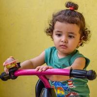 lindo niño pequeño shivaay conduciendo en bicicleta en el balcón de la casa durante el verano, dulce sesión de fotos de niño pequeño durante el día, niño pequeño disfruta de andar en bicicleta en casa durante la sesión de fotos