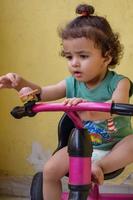 lindo niño pequeño shivaay conduciendo en bicicleta en el balcón de la casa durante el verano, dulce sesión de fotos de niño pequeño durante el día, niño pequeño disfruta de andar en bicicleta en casa durante la sesión de fotos