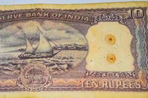 vista de cerca de una rara nota de diez rupias sobre la mesa, viejos billetes de moneda india en una mesa giratoria, vista de cerca de moneda india rara foto