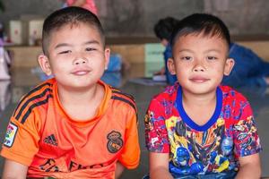 dos niños asiáticos indefinidos sonriendo y mirando la cámara en el interior foto