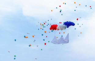 Colorful balloons on blue sky background hanging with white empty nameplate. photo