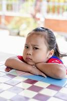 niña enojada sentada y mirando a la cámara. niño infeliz que se siente molesto y triste con una actitud negativa. foto