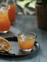 High angle view a glass of orange juice on vintage plate and blurred orange juice jar and window leaf pattern in the back. photo