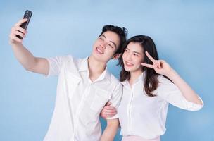 Image of young Asian couple using smartphone on blue background photo