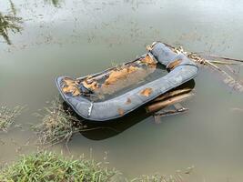 Photo of the wreckage of a broken sofa submerged in water.