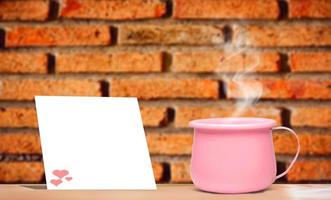 A bright pink metallic coffee cup on vacation.  And there is a blank sheet of note paper for inserting the contents. mock up and copy space photo