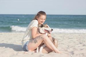 mujer juega con perro en la playa foto