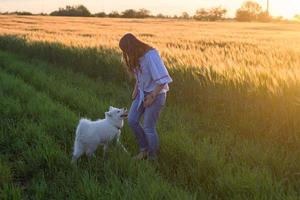 portrait of woman and white puppy of husky dog in the fields photo