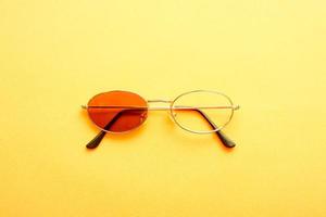 Sunglasses with one missing lens on yellow background. photo